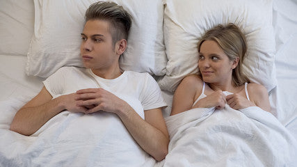 Couple in bed togeather contemplating having sex